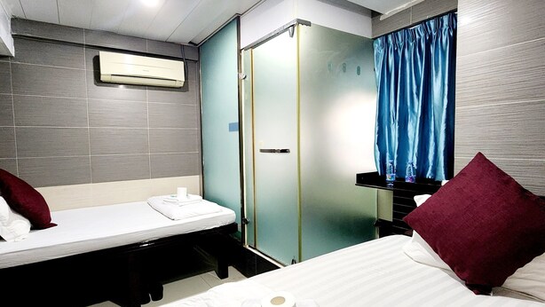 A hotel room with a bed, a smaller bed, a bathroom, and a wardrobe. - KK Hotel  (Kowloon)