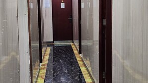 A hallway with a marble floor, doors on both sides, and a door at the end with the number 16. - KK Hotel  (Kowloon)