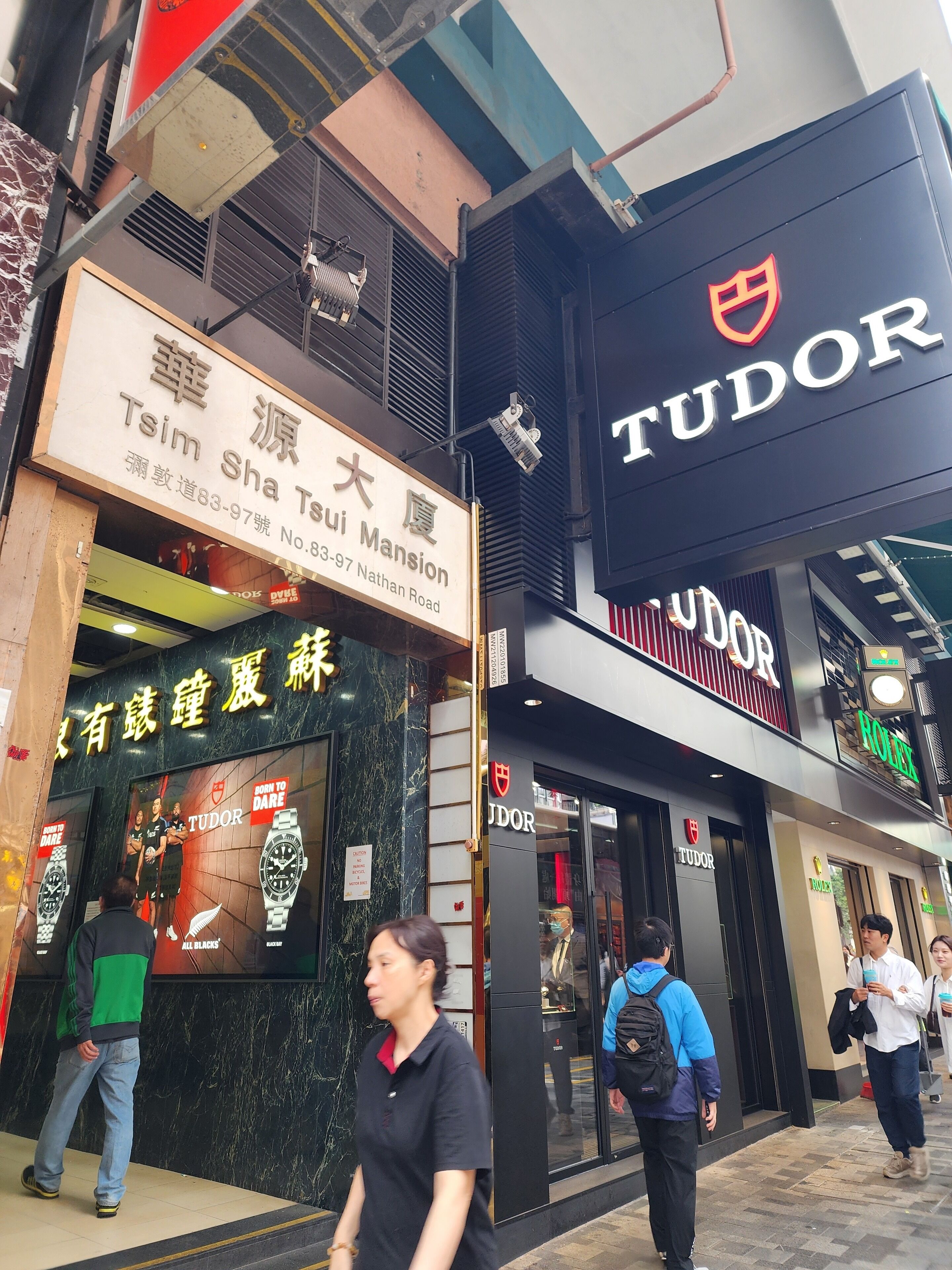 Ein Schaufenster mit einem Schild für 'Tudor' und einem weiteren für 'Tsim Sha Tsuim Mansion'.