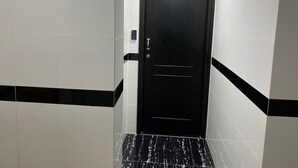 A narrow hallway with white and black tiled walls and a black door with a keypad lock. - KK Hotel  (Kowloon)
