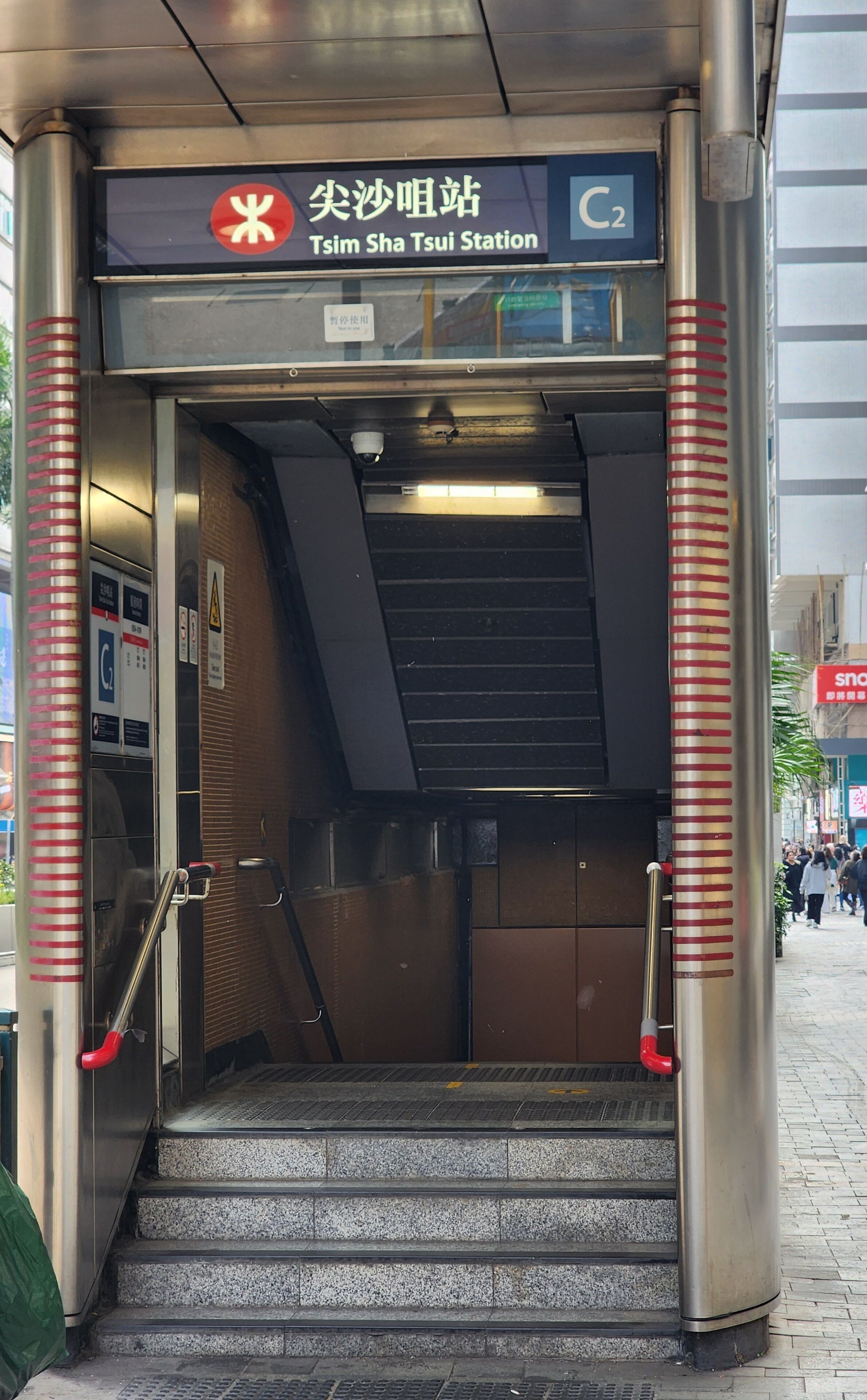 An entrance to Tsim Sha Tsui Station with a staircase leading down.