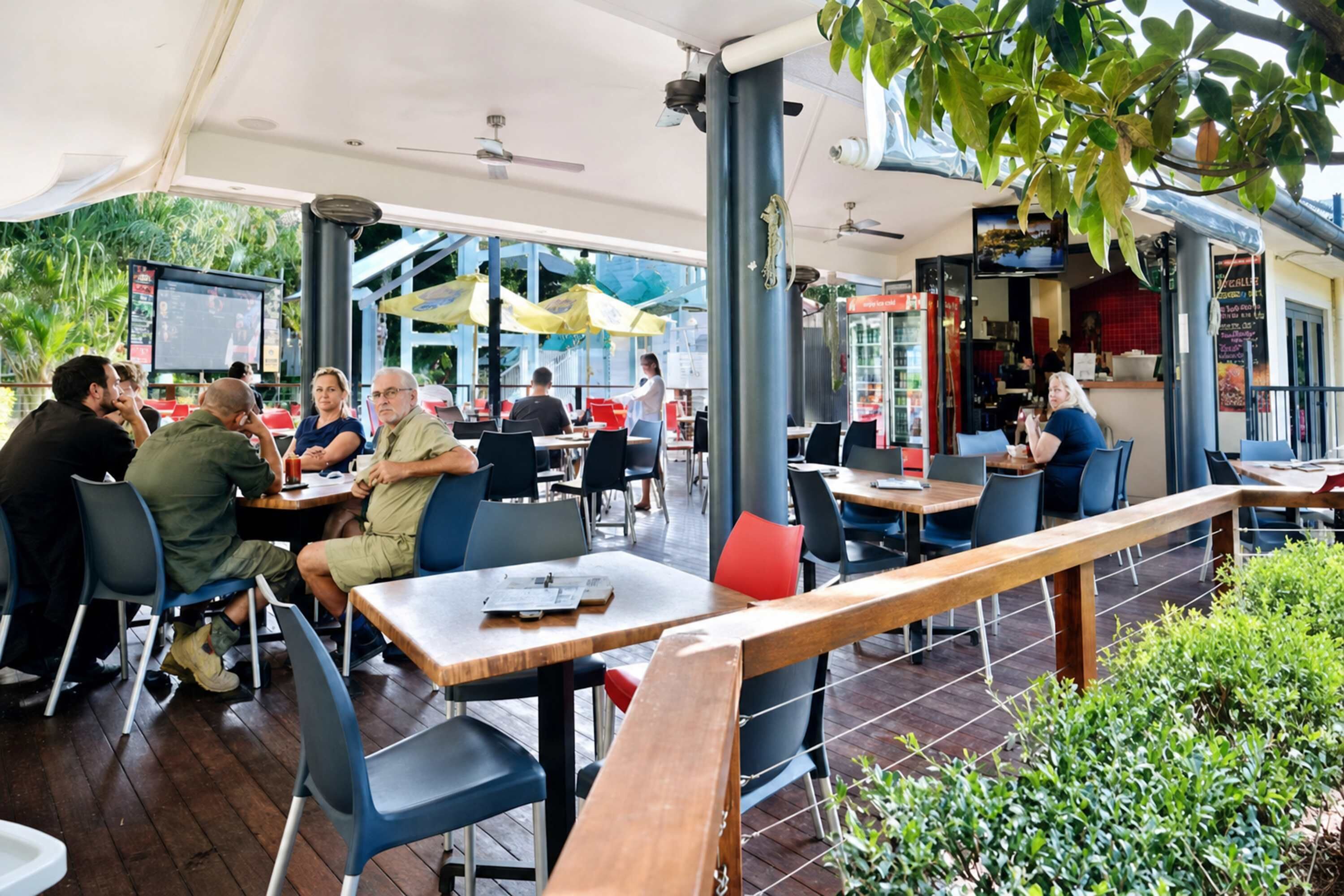 Een terras met tafels en stoelen, parasols en uitzicht op de straat.