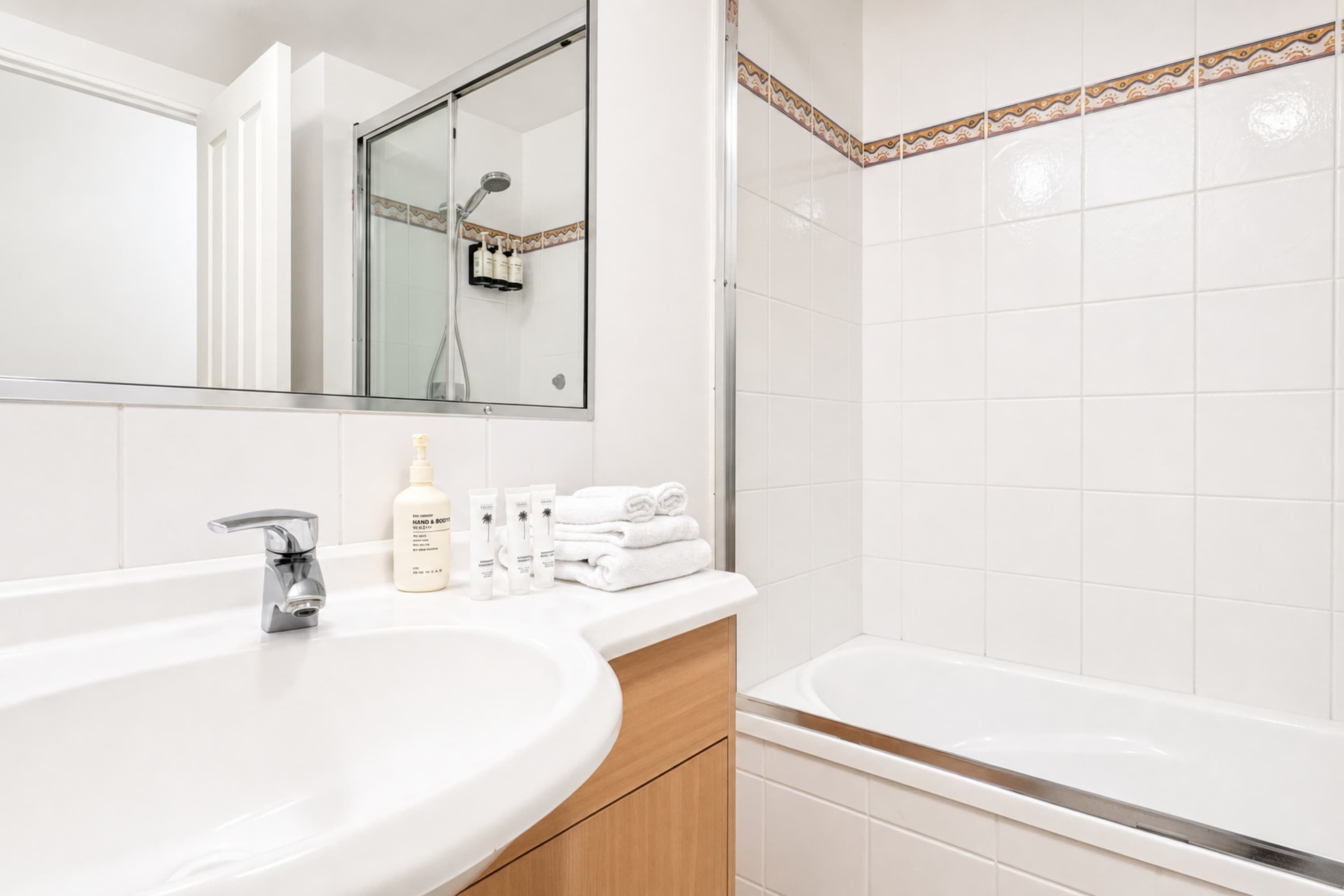 A modern bathroom with a large sink, a mirror, a shower, and a bathtub.