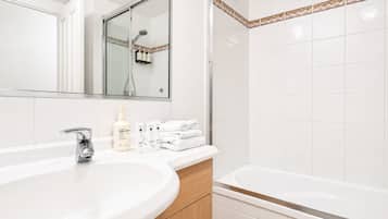 A modern bathroom with a large sink, a mirror, a shower, and a bathtub.