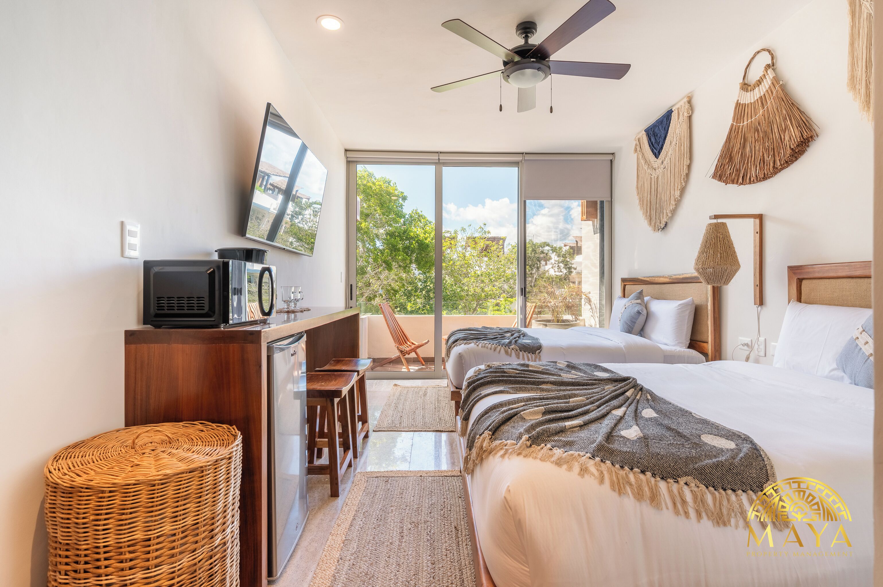 A hotel room with a bed, a desk, a television, and a view of the outdoors.