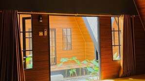 A room with a bed, wooden walls, a window, and a door leading outside. - Dsvarga Glamping (Depok)