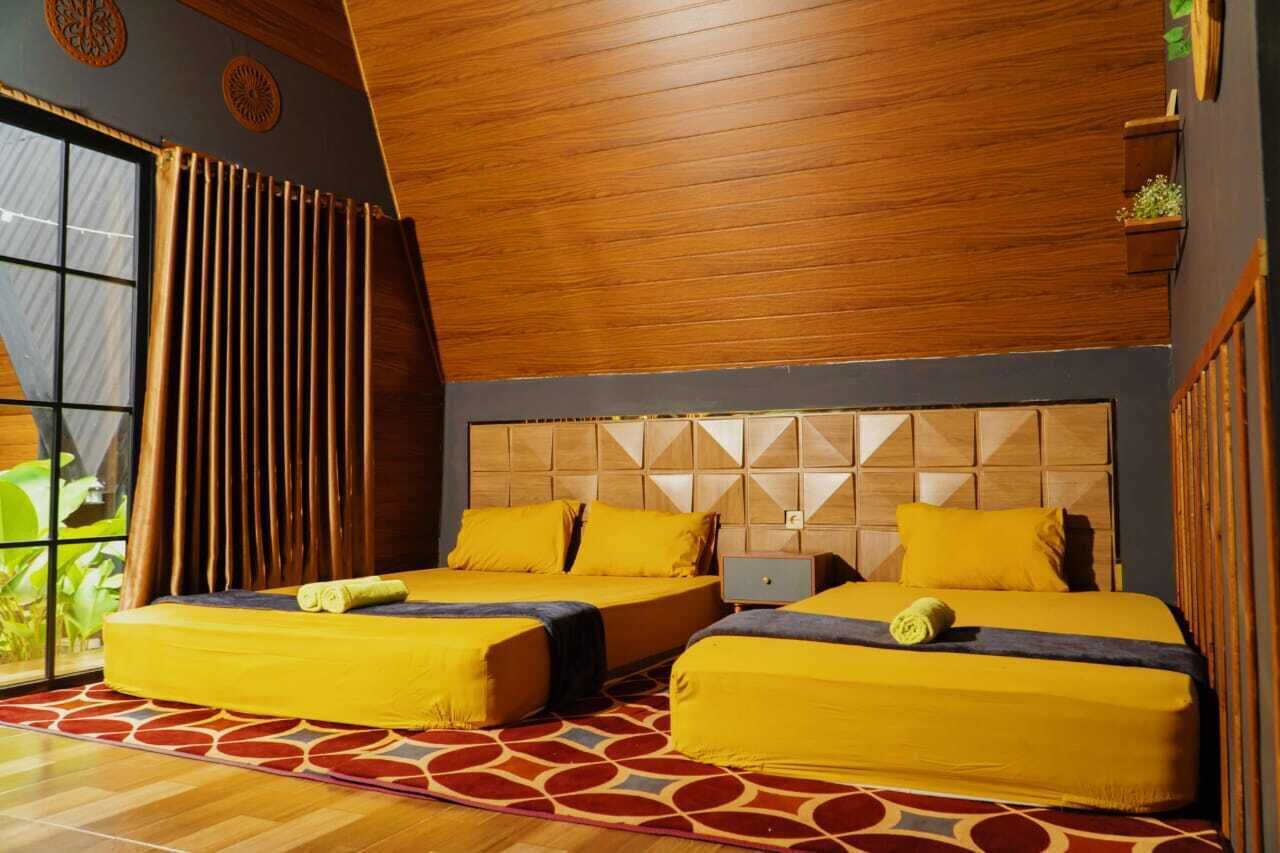 Una habitación con dos camas, paneles de madera en el techo, una alfombra estampada y una ventana con cortinas.