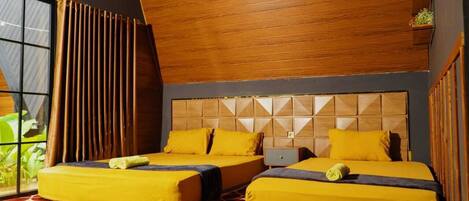 Una habitación con dos camas, paneles de madera en el techo, una alfombra estampada y una ventana con cortinas.
