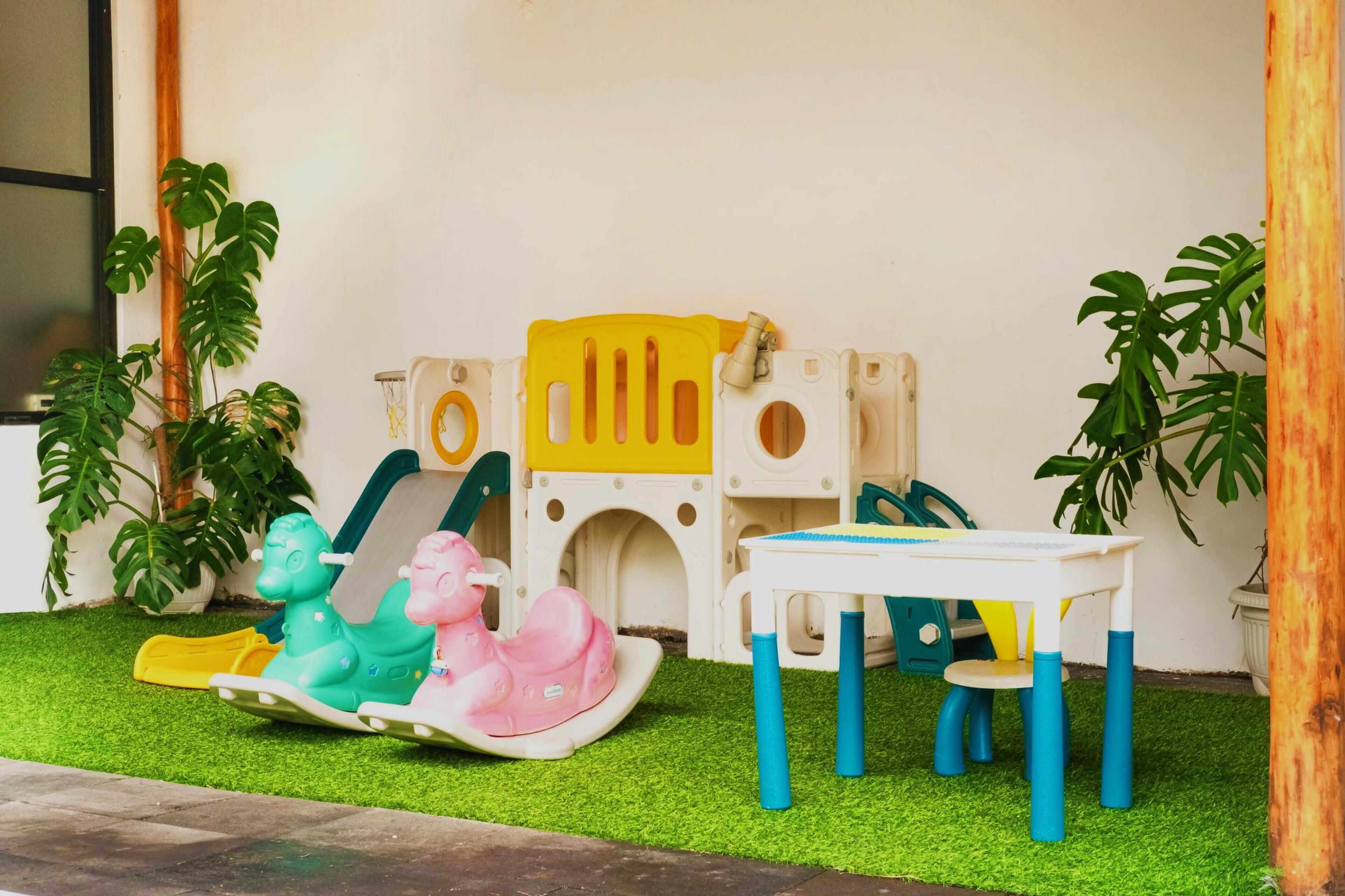 A children's play area with a small table and chairs, a rocking horse, and a play structure.