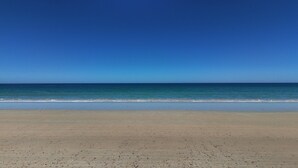 Una playa con cielo despejado y mar tranquilo.