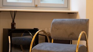 Huoneessa on ikkuna, tuoli, pöytä ja maljakko, jossa on kaisloja.