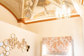 A room with a chandelier, a wall with circular mirrors, and a floral-patterned headboard.