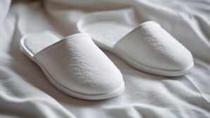 A pair of white slippers on a bed. - Lagrange Turin Suite 07, for a refined stay (Torino)
