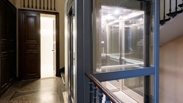 An elevator with a glass door, a wooden door to the left, and a blue handrail. - Lagrange Turin Suite 07, for a refined stay (Torino)