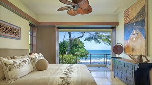 Une chambre avec un grand lit, une vue sur l’océan et un balcon.