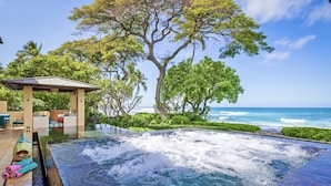 Un bain à remous avec vue sur l’océan, entouré d’une végétation luxuriante et agrémenté d’un belvédère.