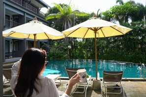 A poolside area with lounge chairs and umbrellas, a swimming pool, and lush greenery. - Kokotel Khao Lak Montana (Takua Pa)