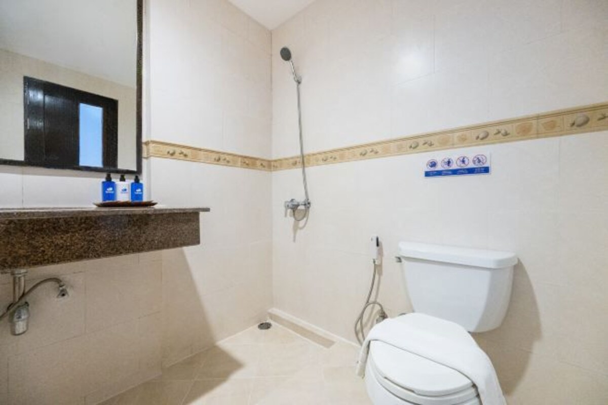 Une salle de bain équipée de toilettes, d’une douche et d’un lavabo avec des distributeurs de savon.