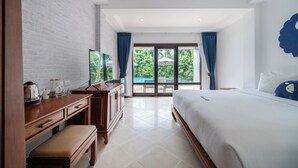 Ein Hotelzimmer mit einem großen Bett, einem Holztisch mit einer Bank, einem Fernseher und Blick ins Freie durch eine Glastür.