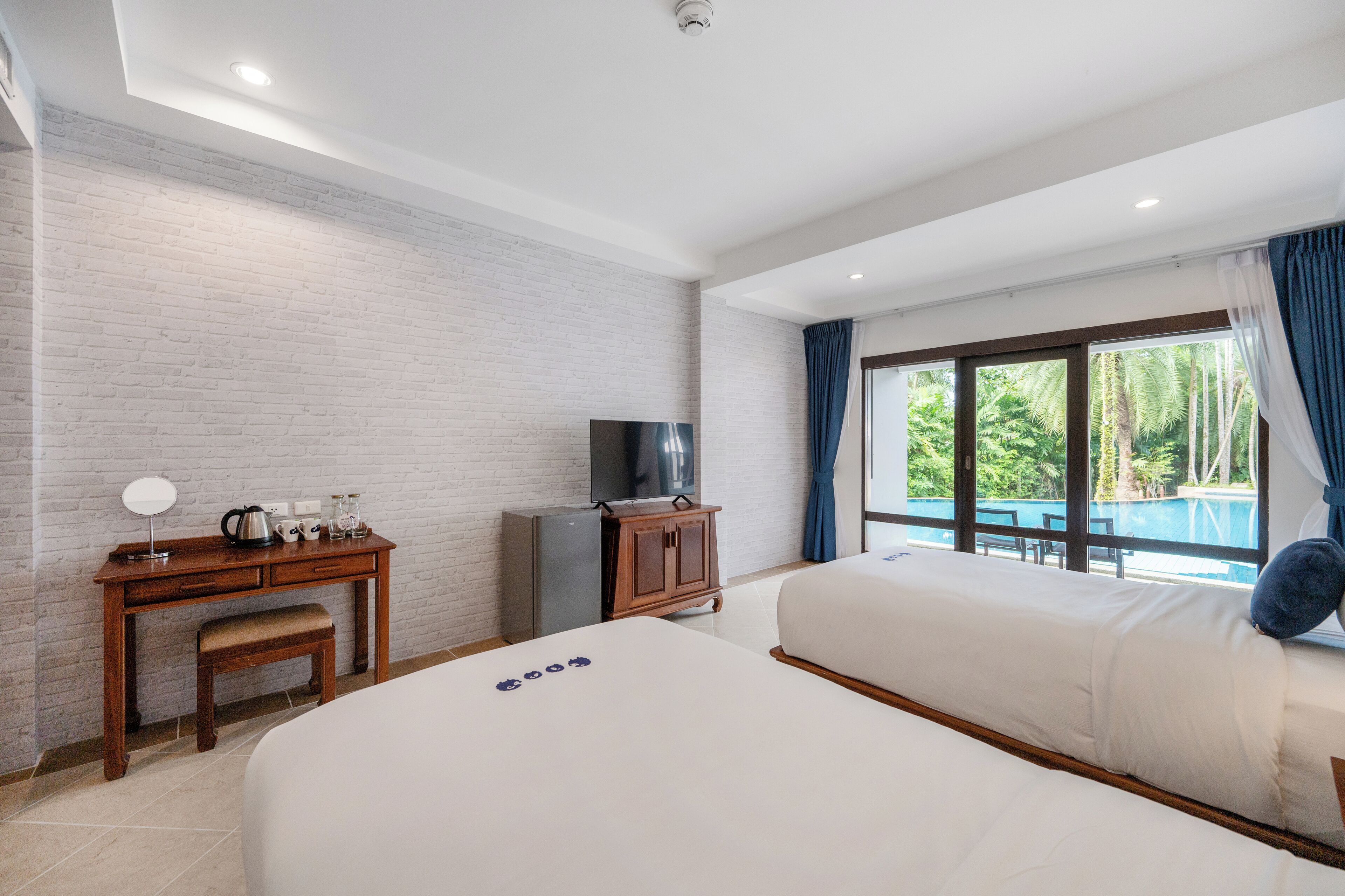 Ein Hotelzimmer mit Bett, Schreibtisch mit Fernseher, einer Kaffeemaschine und Blick ins Freie.