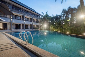 A swimming pool with a tiled edge, surrounded by a building with multiple balconies and a covered outdoor area. - Kokotel Khao Lak Montana (Takua Pa)