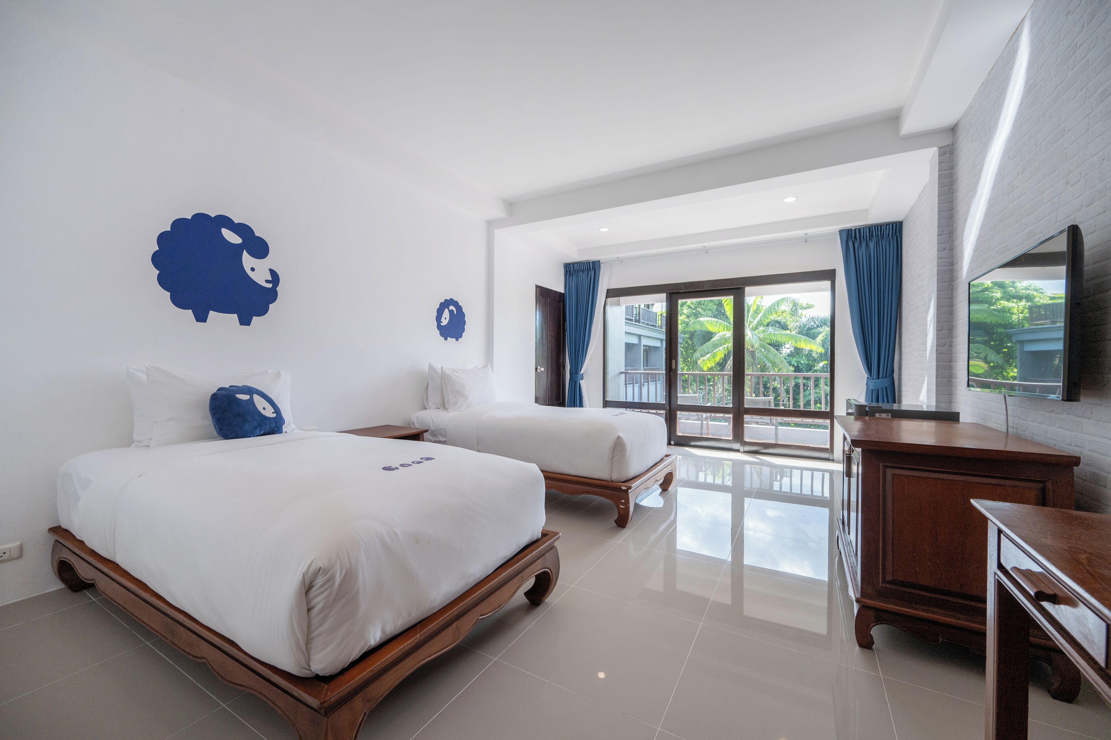 A hotel room with two beds, a wooden dresser, and a large window with curtains.