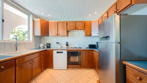 Une cuisine moderne avec des meubles en bois, un lave-vaisselle, un réfrigérateur et une fenêtre qui laisse entrer la lumière naturelle.