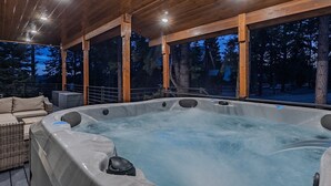 A hot tub in an outdoor wooden deck with a view of trees and a house in the background. - Duck Creek Luxury Cabin w/ Hot Tub | Las Hermanas (Kane County)