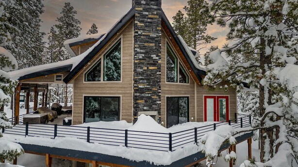 A modern, multi-story cabin with a stone facade, large windows, and a covered deck. - Duck Creek Luxury Cabin w/ Hot Tub | Las Hermanas (Kane County)