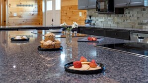 Une cuisine dotée de plans de travail en granit, d’une cuisinière en acier inoxydable et de meubles en bois.