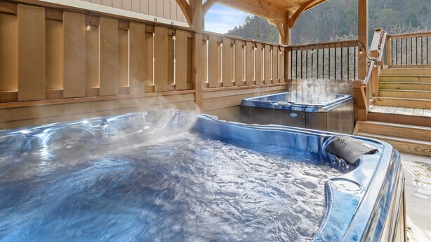 Une terrasse en bois avec deux bains à remous, située sous une zone abritée.