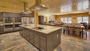 Une cuisine spacieuse dotée de plans de travail en granit, d’appareils électroménagers en acier inoxydable et d’un grand îlot central.