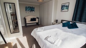 Una camera da letto con un letto grande, un comodino, una sedia, un armadio e un quadro appeso al muro.