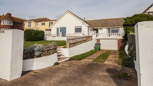 Un edificio residenziale con facciata bianca, un giardino anteriore e un vialetto che conduce a un garage.