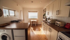 Una cucina con lavatrice, tostapane e vista mare.