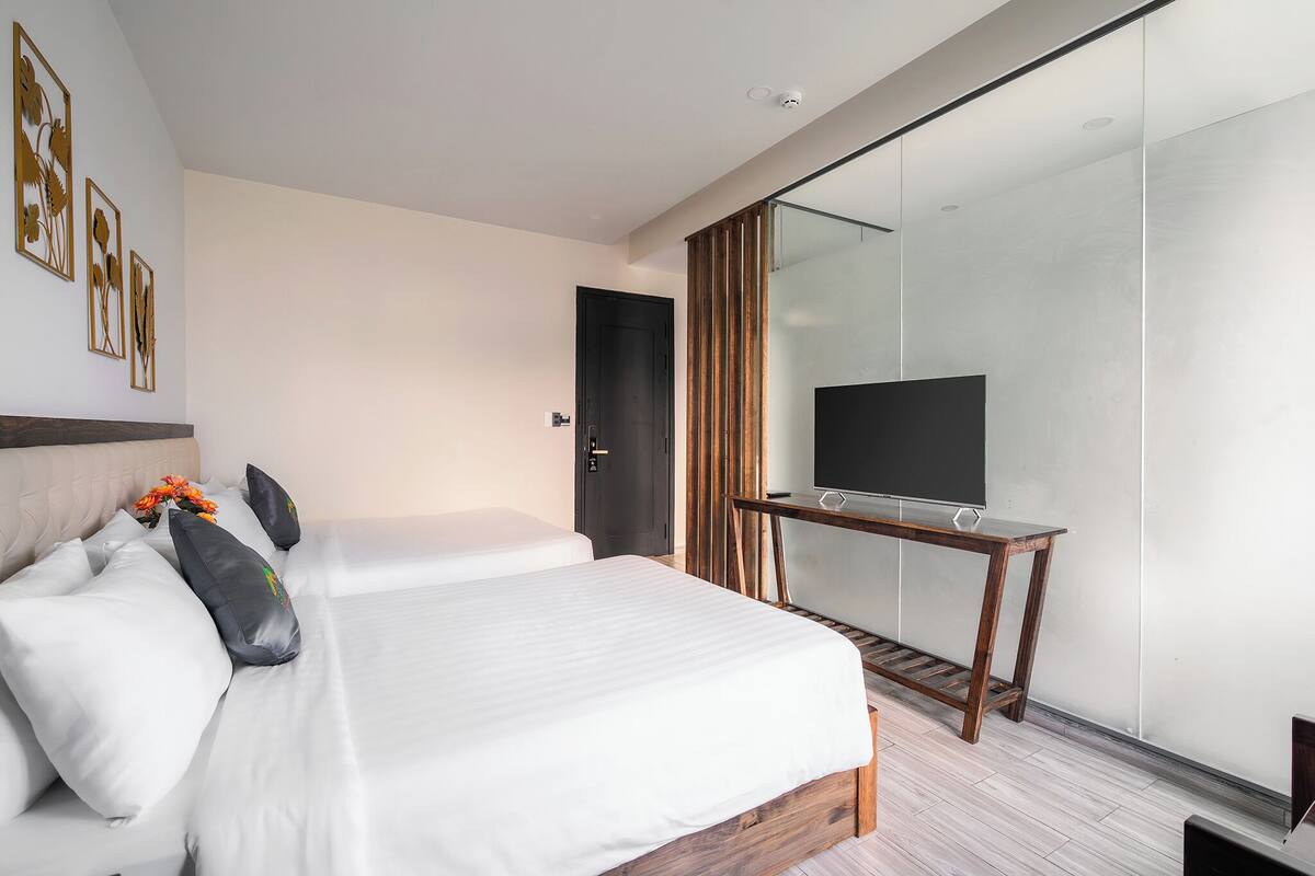 Una habitación de hotel moderna con una cama grande, un escritorio con televisor de pantalla plana y una puerta corrediza de vidrio que da a un balcón.