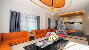 A hotel lobby with orange sofas, a Christmas tree, and a reception desk. - Greenview City Hotel (Xuan Huong - Da Lat)