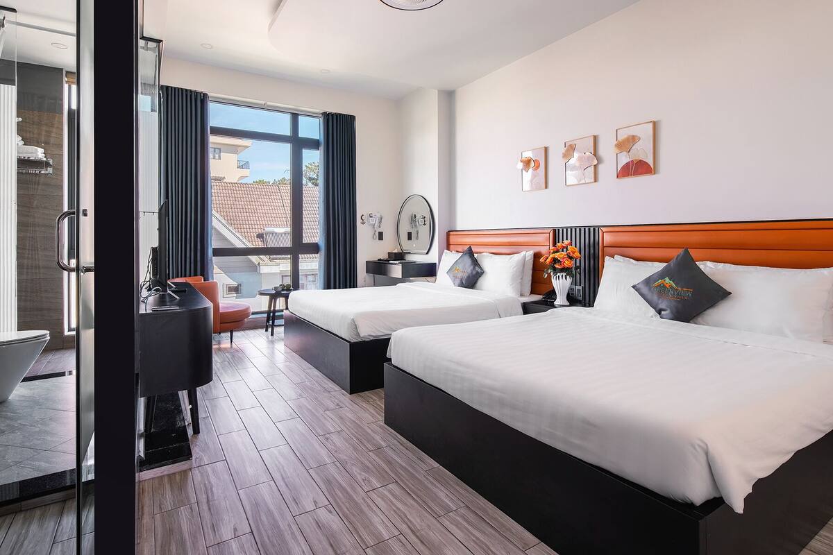 Habitación de hotel moderna con dos camas, un escritorio, una silla y vistas a la ciudad.