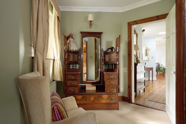 A room with a large wooden dresser, a mirror, and a chair. There is a door leading to another room.