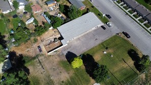 Luchtbeeld van een groot gebouw met een plat dak, omringd door een parkeerplaats en een gazon.