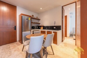 Eine kompakte Küche mit Kühlschrank, Mikrowelle und Kaffeemaschine. Ein Esstisch bietet Platz für vier Stühle.