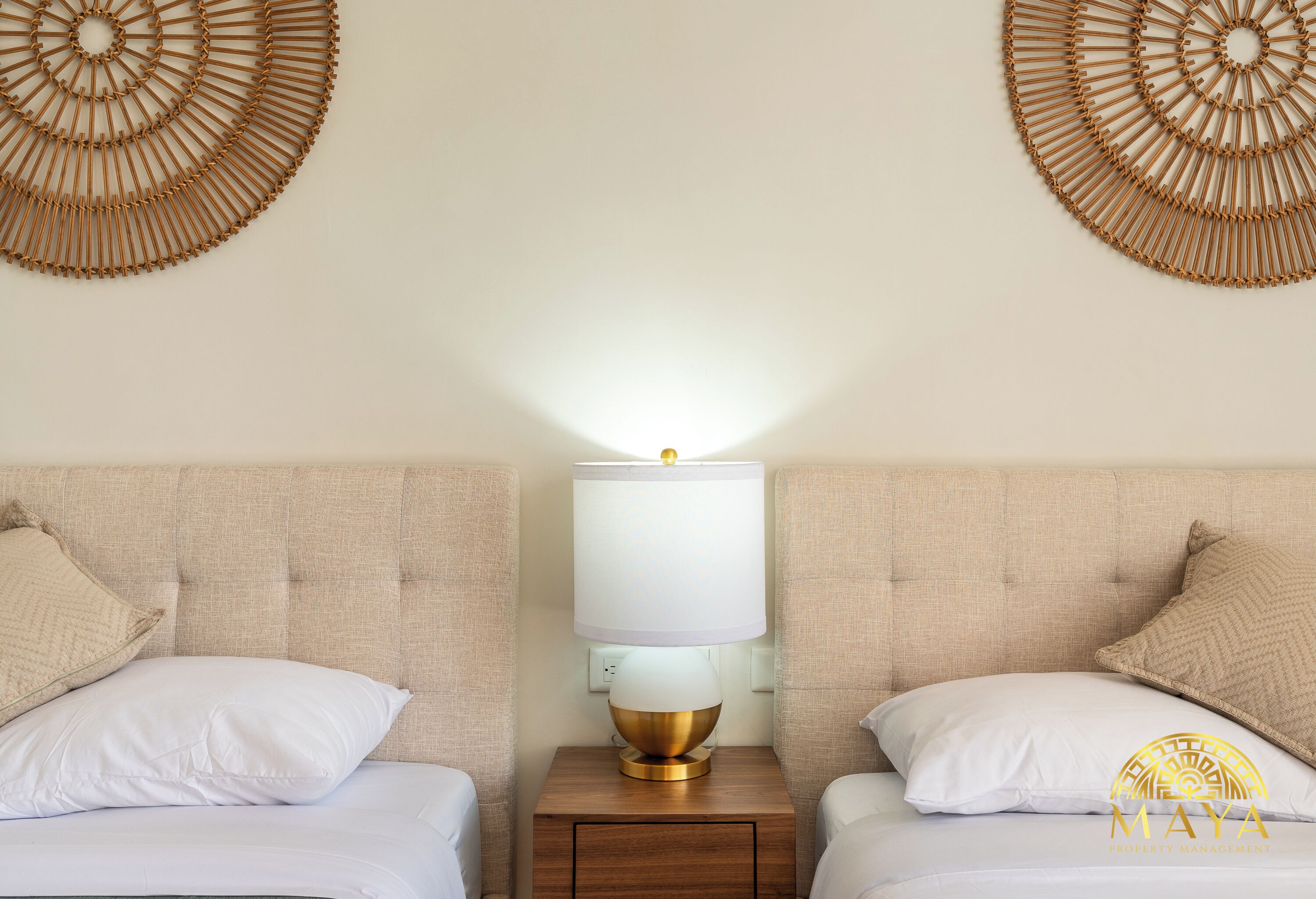 A hotel room with two beds, a nightstand with a lamp, and decorative wall art.