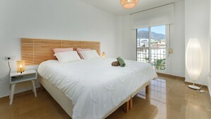 Une chambre à coucher comprenant un lit, des lampes de chevet, une table de chevet, une fenêtre avec vue et un lampadaire.