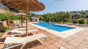 Ein Swimmingpool mit Liegestühlen und Strohdächern.