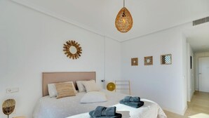 Un dormitorio moderno con una cama grande, dos mesitas de noche, una lámpara colgante y decoración en la pared.