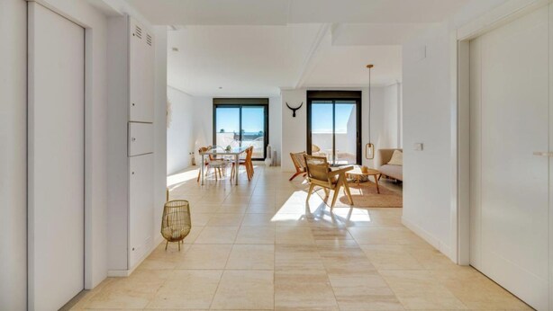 Amplia sala de estar moderna con una mesa de comedor y sillas, un sofá y un ventanal que ofrece vistas al exterior.
