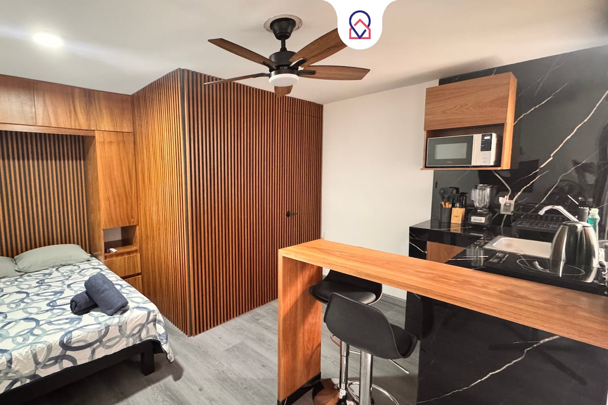 Une chambre moderne avec un lit, un bureau et un coin cuisine.