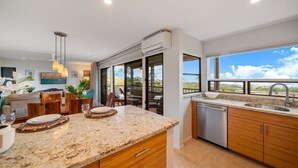 Una cocina moderna con encimeras de granito, armarios de madera y un amplio ventanal con vistas panorámicas.