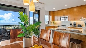Una cocina moderna con armarios de madera, una isla central y un comedor con vista al océano.