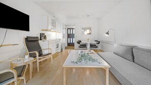 Un saló modern i ben il·luminat, amb un sofà gris, una taula de centre de fusta i un televisor fixat a la paret.